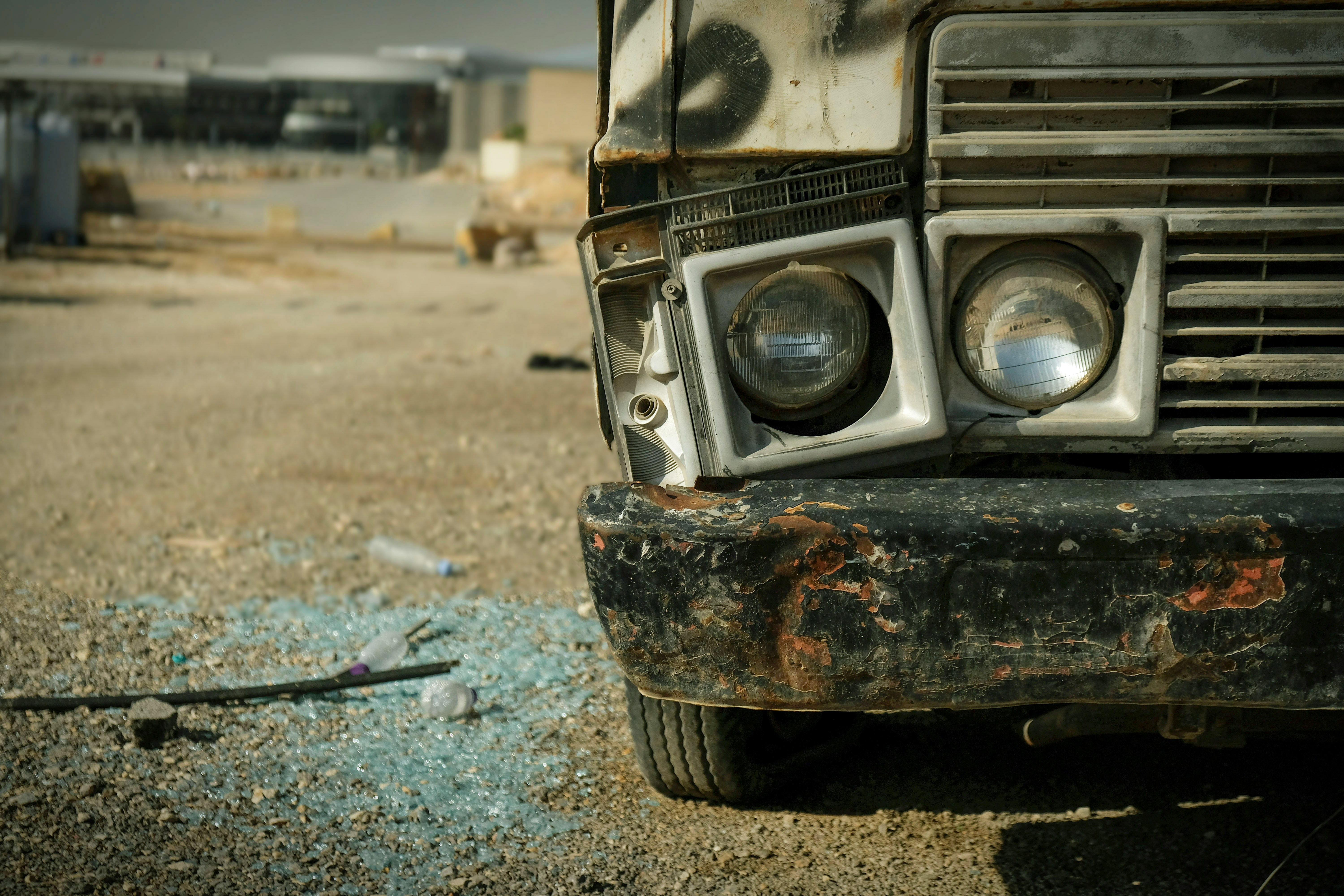 Damaged front corner of a bus with broken glass on the ground